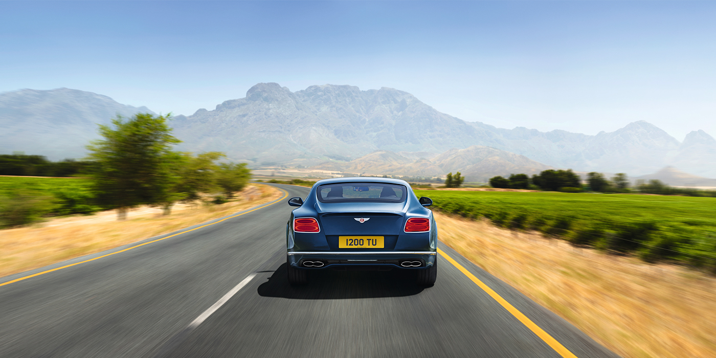 Bentley Zug Bentley Pre Owned Bentley Continental GT in Marlin blue paint seen from rear on country road