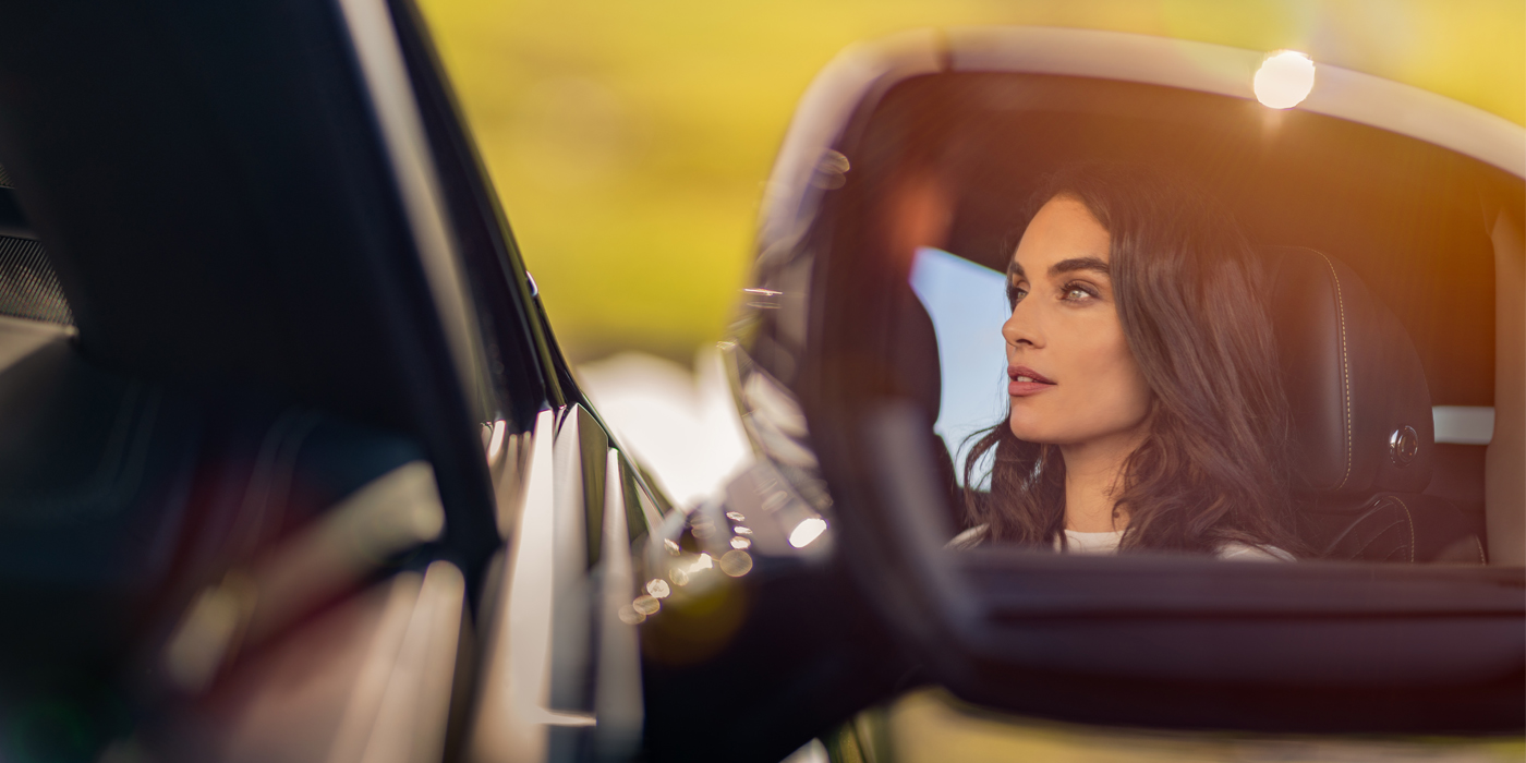 Bentley Zug profile of dark haired woman's face in mirror of Bentley car in sunlight