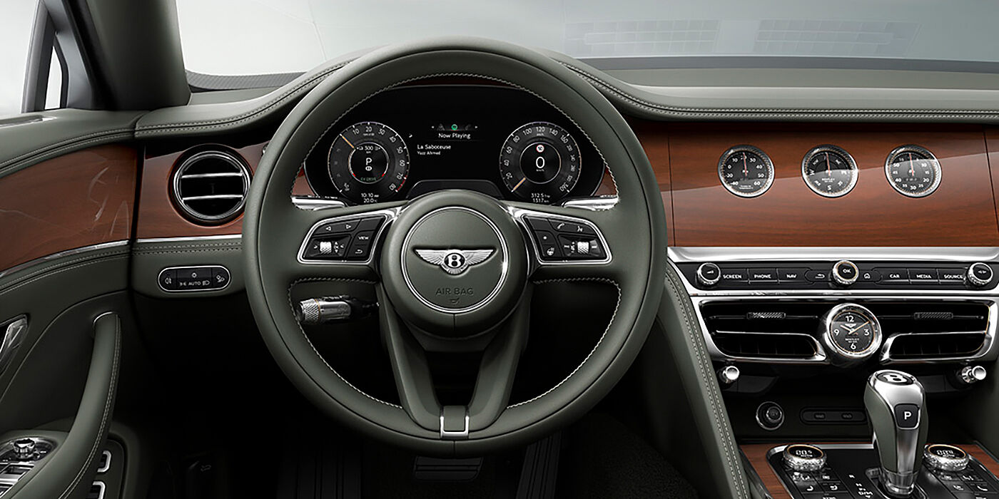 Bentley Zug New Bentley Flying Spur sedan front cabin in Cumbrian Green hide and Crown Cut walnut veneer showing steering wheel and Rotating Display with three clocks on face