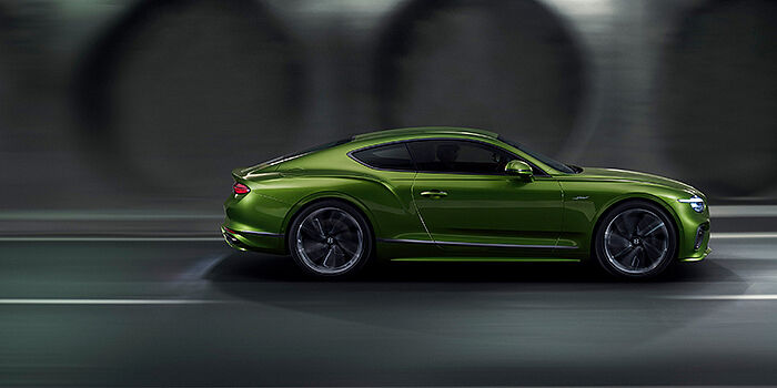  Bentley Zug Bentley Continental GT coupe in Tourmaline Green paint driving in profile on a dark road