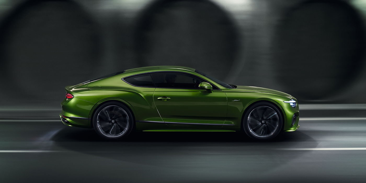 Bentley Zug Bentley Continental GT coupe in Tourmaline Green paint driving in profile on a dark road