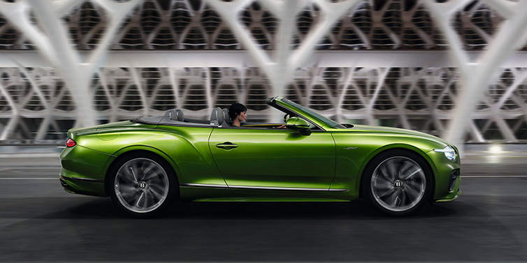 Bentley Zug Bentley Continental GTC Speed convertible side profile in Tourmaline Green paint driving dynamically on a bridge at night