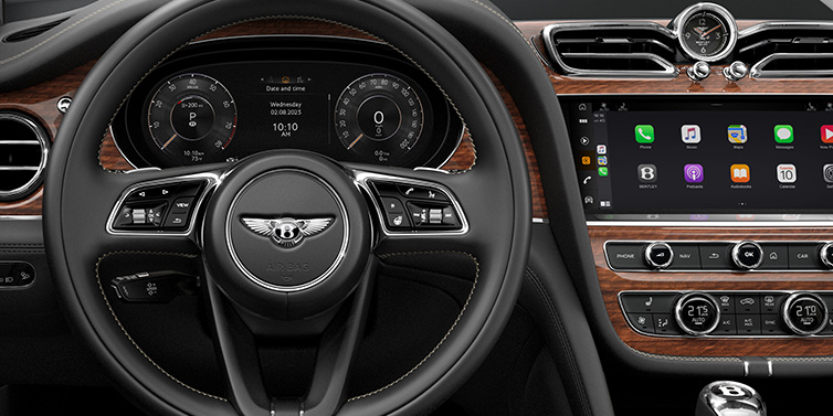 Bentley Zug Bentley Bentayga SUV front interior detail of steering wheel and driver screens surrounded by Beluga black hide and Crown Cut Walnut veneer